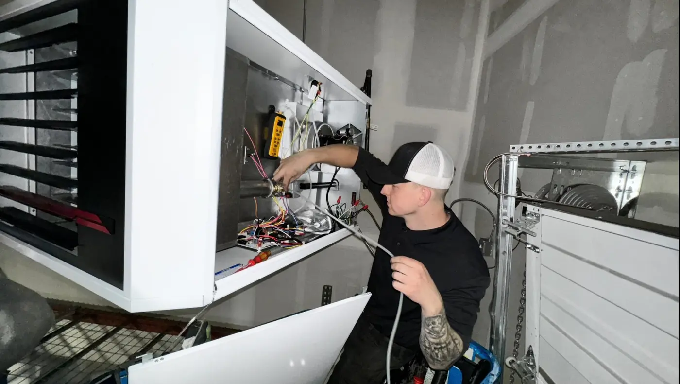 Carson Brender of AeroCool HVAC servicing the control panel of an air handler